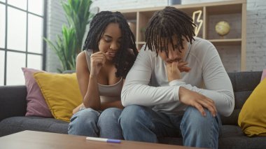 Endişeli genç bir çift, kapalı bir koltukta oturup hamilelik testinin sonucunu merakla bekliyor..