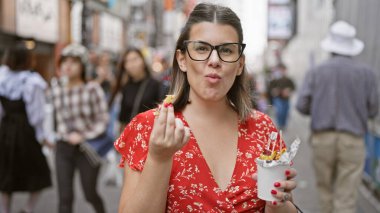 Göz kamaştırıcı İspanyol kadın tatlı patates aperatiflerinin tadını çıkarıyor. Vızıldayan Osaka 'nın dotonbori sokağında.