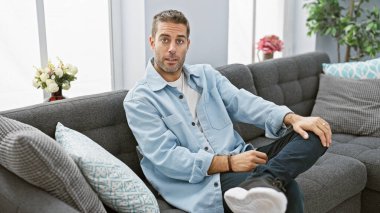 Modern oturma odasındaki kanepede uzanan sakallı sıradan bir genç adam..