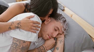 Dövmeli bir çift sıcak bir yatak odasında dinlenirken sarılır, sevgi, şefkat ve rahatlık temaları uyandırır..