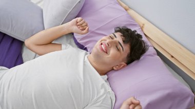 Neşeli genç bir adam rahat bir yatak odasında uyanıyor, mutluluk ve memnuniyeti ifade ediyor..