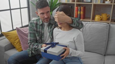Erkekler, rahat oturma odasındaki kanepede hediyelerle kadınlara sürpriz yaparlar.