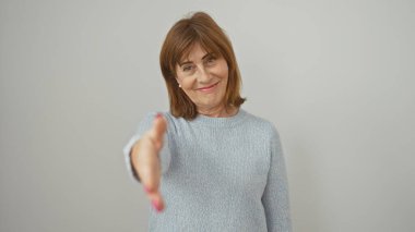 Beyaz bir arkaplan karşısında el sıkışan olgun bir kadın, hoş geldin, anlaşma ya da tanıtım sunuyor..
