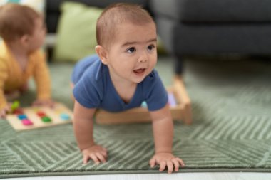 Sevimli Çinli çocuk gülümseyerek evde yerde sürünüyor.