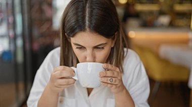 Genç, güzel, İspanyol bir kadın restoranda masada kahve içiyor.