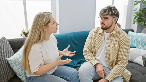 stock image A woman and a man seated indoors engage in a serious conversation in a modern living room, expressing emotions and relationship dynamics.