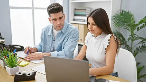 stock image A man and woman coworking in a modern office with a laptop, discussing a project attentively.