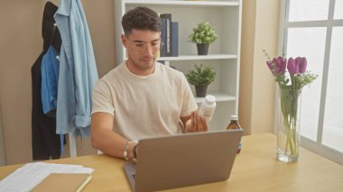 Genç bir İspanyol evdeki ilaçları inceliyor. Etrafı dizüstü bilgisayarlarla, kağıtlarla ve çiçeklerle çevrili. Samimi bir iç mekan yaratıyor..