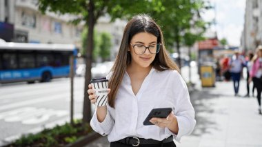 Madrid sokaklarında akıllı telefon kullanarak gülümseyen güzel İspanyol kadın.