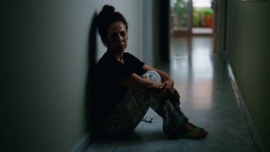 Orta yaşlı İspanyol kadın aile içi şiddet yüzünden acı çekiyor. Gözlerinde morluklar var. Evinde yerde oturuyor.