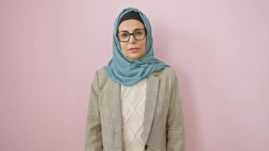 Kuşkucu orta yaşlı İspanyol kadın tesettüre girmiş, ağzı açık alaycı görünüyor, pembe izole edilmiş arka plandan şoke olmuş.