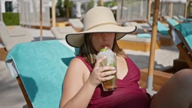 Lüks bir tatil köyünde havuz başında mojito içen bir kadın.
