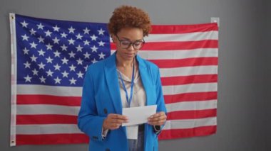 Afrika kökenli Amerikalı kadın bizimle kapalı alanda oy veriyor. Bayrak arkaplanı, yurttaşlık ve demokrasi yayıyor..