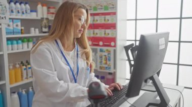 Profesyonel bir kadın eczacı, modern bir eczanedeki bilgisayara danışıyor.