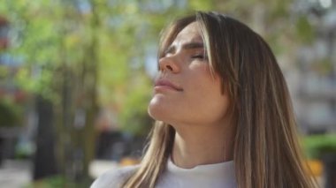 Şehir parkında dingin bir anın tadını çıkaran genç bir kadın. Etrafı yemyeşil ve güneş ışığıyla çevrili..