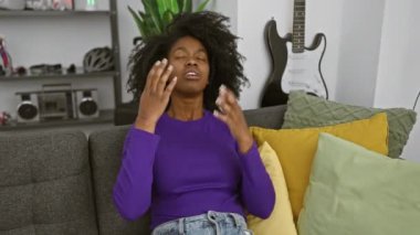 Modern bir oturma odasında kendini stresli hisseden Afrikalı bir Amerikalı kadın..