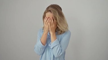 Gömlek giyen umutsuz sarışın genç kadın, beyaz soyutlanmış arka plana karşı tek başına dur, yüzünü ellerle ört, endişelerini ve depresyonlarını haykır..