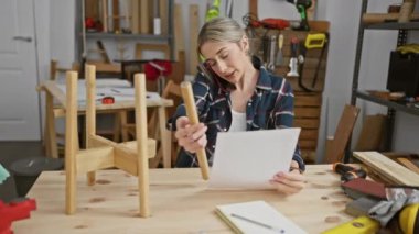 Odaklanmış bir marangoz, iyi donanımlı bir atölyede bir belgeyi inceliyor..