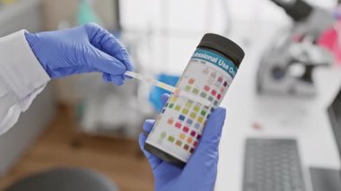 Laboratuvarda çalışan bir sağlık uzmanı idrar tahlili için dipstick kullanır. Bu da kapalı alanda tıbbi teşhisi gösterir..