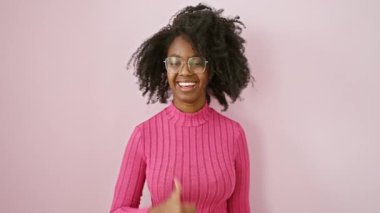Çekici Afro-Amerikan kadın gözlüklü, geniş bir şekilde gülümseyen, baş parmağını kaldırmış, reklam için mükemmel bir ürün sergiliyor.!