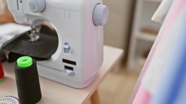 Kumaş ve araçlarla çevrili atölyedeki dikiş makinesinde çalışan odaklanmış terzi