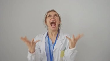 Hüsrana uğramış beyaz kadın doktor önlüğü giymiş bağırıyor ve öfkesini kusuyor. Kollar havada, beyaz arka planda izole edilmiş çılgın bir ifade..
