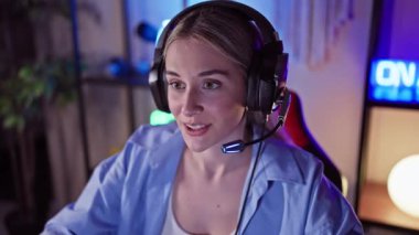 Renkli bir oyun odasında kulaklık takan odaklanmış genç bir kadın.