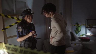 Polis kadın, sarı bantlı, kapalı bir suç mahallinde bir adamı sorguluyor.