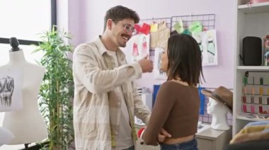 Terzi ve kadın, moda tasarımları ve dikiş aletleriyle çevrili renkli bir atölyede mutlu bir şekilde etkileşime geçiyorlar..