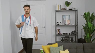 Elinde steteskop olan Latin kökenli genç bir adam işten sonra eve geliyor, rahat bir oturma odasının arka planında..