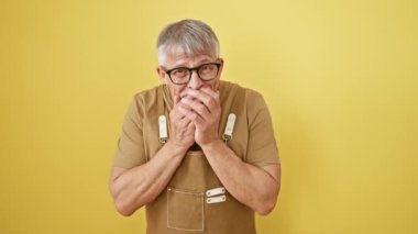 Neşeli, gri saçlı, orta yaşlı, gözlüklü, gözlüklü ve önlüklü adam utançla gülüyor, sarı duvarın üzerinden ağızdan ağıza gülüyor, dedikoduyu kucaklıyor.