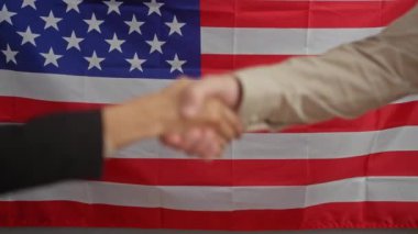 Amerikan bayrağının önünde el sıkışan bir erkek ve kadın Amerika 'da siyasi bir anlaşmayı ya da ortaklığı simgeliyor..