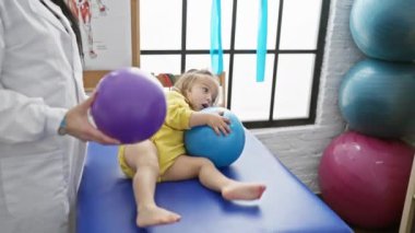 Beyaz önlüklü kadın fizyoterapist rehabilitasyon odasında genç hastaları tedavi etmek için egzersiz topları kullanıyor.