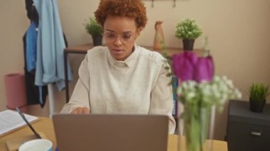 Kızgın Afro-Amerikalı kadın evde oturmuş, öfkeyle yumruğunu kaldırıyor. Delilik, öfke ve saldırganlık onun ateşli ifadesinden yayılıyor..