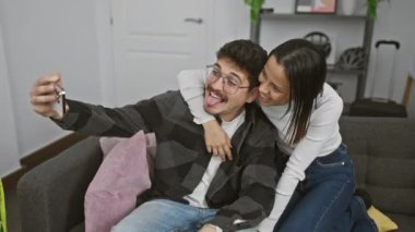 Mutlu bir çift şık bir oturma odasında rahat bir koltukta selfie çekiyor..