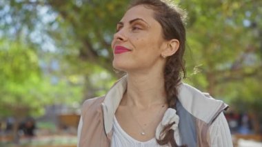 Dalgın genç bir kadın, yemyeşil bir parkta doğal güzellik ve sükunet saçan huzurlu bir anın tadını çıkarıyor..