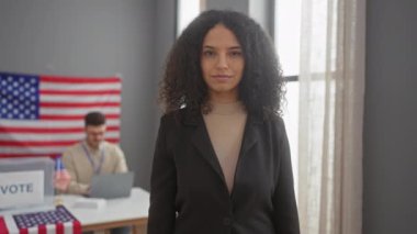 Gülümseyen bir kadın, arkasında Amerikan bayrağıyla çalışan bir adam varken 