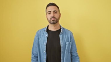 Sportif ve zinde İspanyol genç adam güçlü kas gücünü gösteriyor sarı arka planda izole edilmiş kot gömlek giyiyor sağlıklı, atletik bir yetişkinin yaşam tarzı portresi.