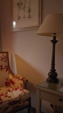Sıcak bir ev ortamında döşenmiş sandalye, masa, lamba, perde ve sanat eserleriyle iç içe..