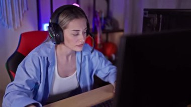 Karanlık bir oyun odasında heyecanlı ve kazanan bir jest yapan genç bir kadın..