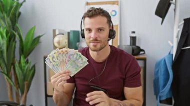 Kulaklık takmış sakallı genç adam, elinde Romanya lei banknotları tutuyordu. Ofiste şaşkın bir ifade vardı, ağzı tamamen açıktı.