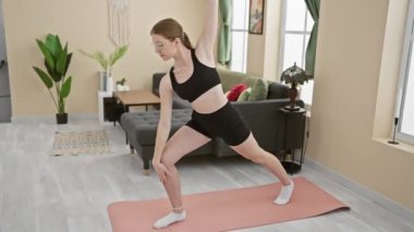 Geniş bir oturma odasında yoga yapan genç bir kadın modern dekor ve doğal ışıkla.