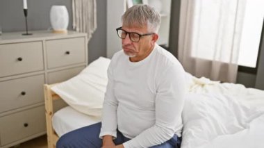 Stresli, orta yaşlı, gri saçlı, pijamalı bir adam, yatak odasında depresyonla boğuşuyor. Üzgün, kederli ifadesi kaygı dolu, ayakta ağlarken, yatağına kızgın..