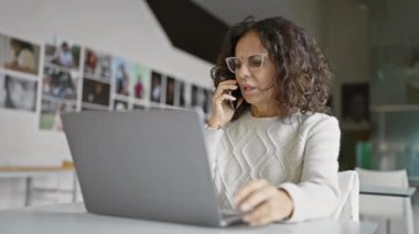Modern ofis ortamında telefonla konuşan profesyonel İspanyol kadın.