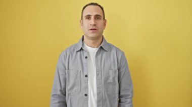 Sarı giysili İspanyol bir adam, gömlek giyen genç bir adamın pozitif ışıltılı bir portresi, özgüvenle gülümsüyor ve çapraz kollarıyla havalı bir poz veriyor..