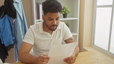 Gülümseyen Afrikalı adam evde evrak okuyor.