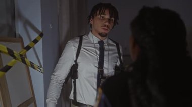 Karanlık bir odada elinde dikkat bandıyla bir suç mahalli soruşturması olduğunu öne süren bir adam ve kadın..