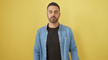 Yeter artık! Hüsrana uğramış, kot gömlekli genç adam, elinde jest, sarı izole arka planda acı içinde duruyor.