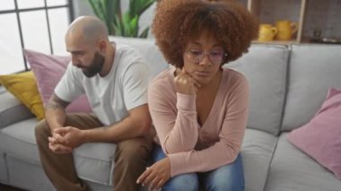 Düşünceli bir kadın ve erkek bir koltukta yan yana oturur, gergin ya da evcil bir atmosferde anlaşmazlık önerirler..