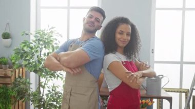 Çiçekçide çapraz kolları ve başparmakları olan bir kadın ve erkek bahçıvan..